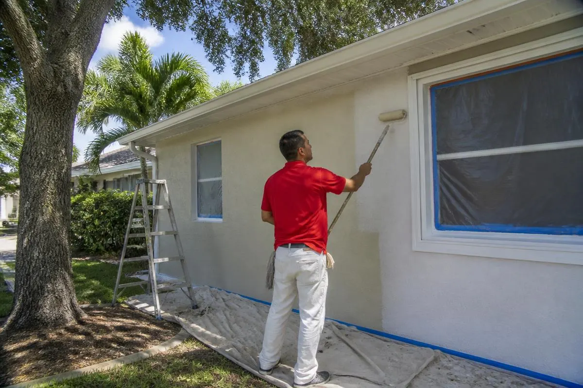 Professional painter rolling fresh exterior paint on a block home in Mulberry, FL for John Crouthers Painting